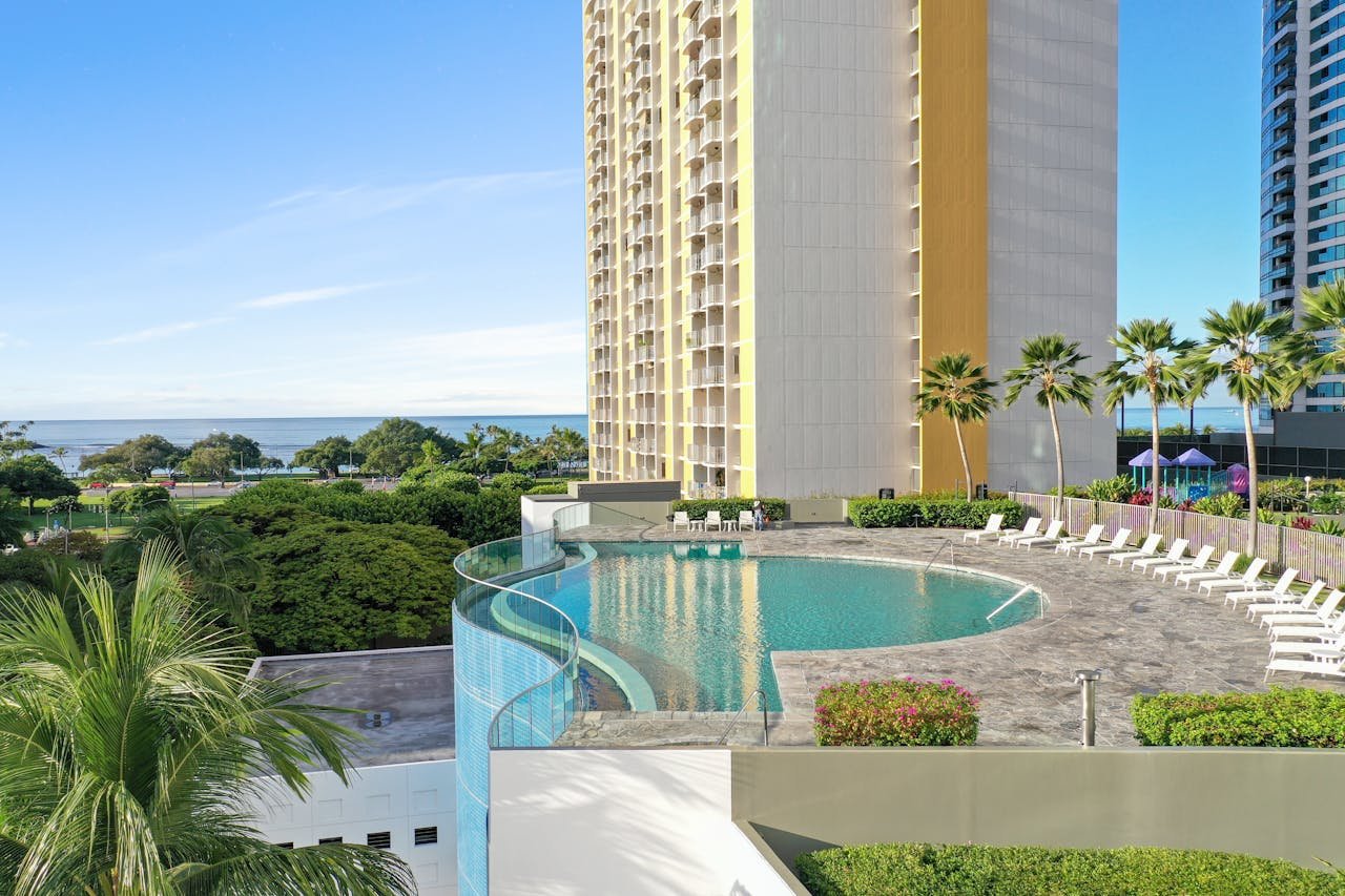 A modern luxury hotel with an infinity pool overlooking the beach in Honolulu, Hawaii.